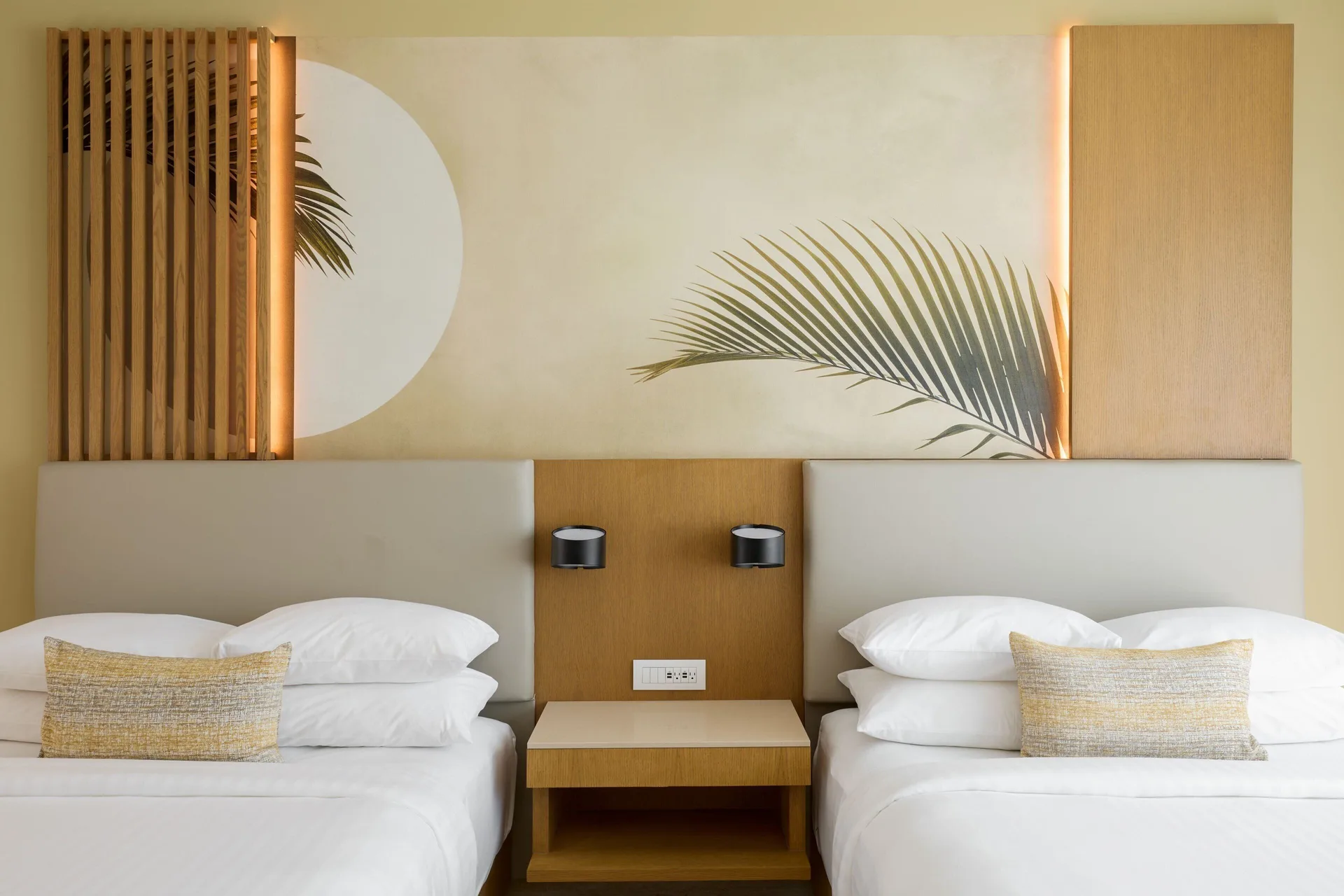 Two double beds with palm-inspired wall art in a guest room at Marriott Cancun.