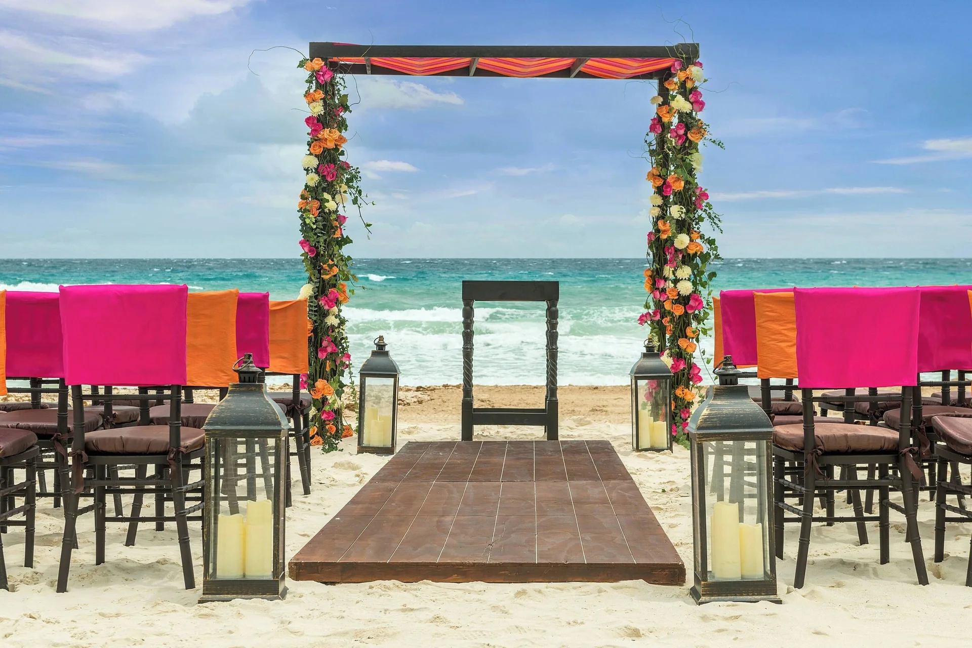 Beach wedding aisle with floral arch and ocean backdrop at Marriott Cancun.