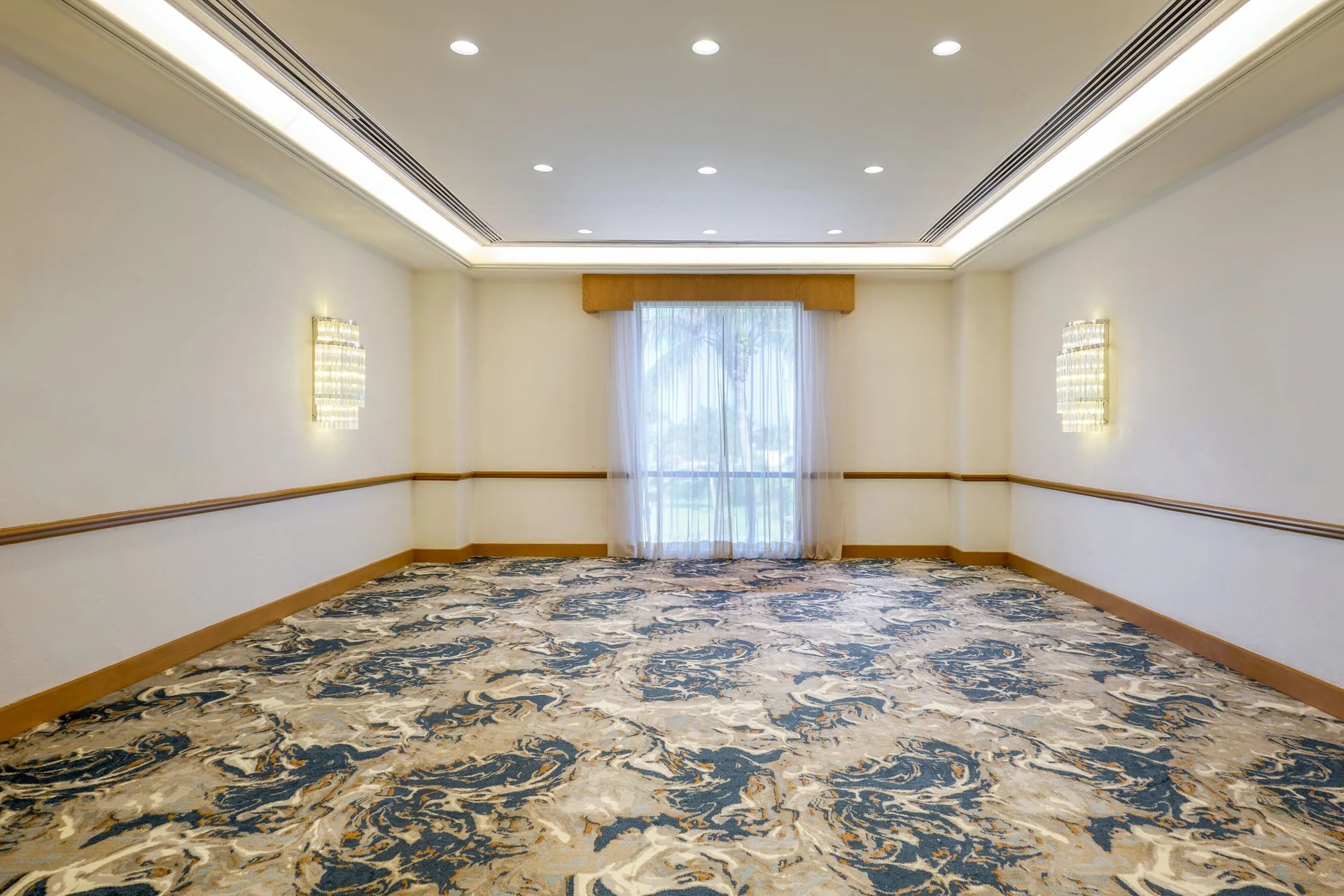 Narrow meeting room with patterned carpet and a curtained window at Marriott Cancun.
