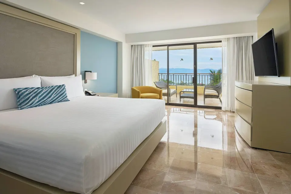 King guest room with balcony seating and wall-mounted TV at Marriott Puerto Vallarta Resort & Spa.
