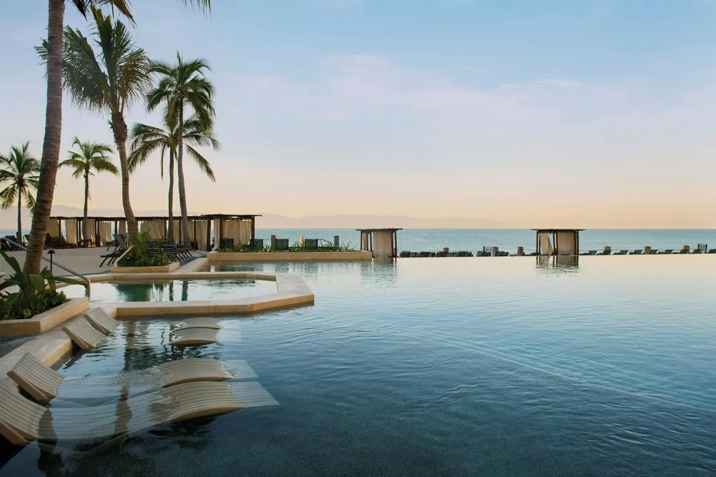 Oceanfront infinity pool with submerged loungers at Marriott Puerto Vallarta Resort & Spa.