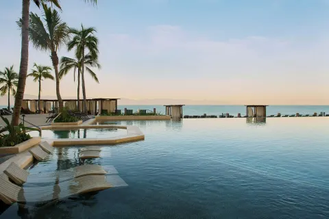 Oceanfront infinity pool with submerged loungers at Marriott Puerto Vallarta Resort & Spa.