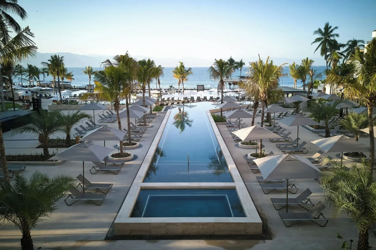 Palm-lined pool deck and beach at Marriott Puerto Vallarta Resort & Spa.