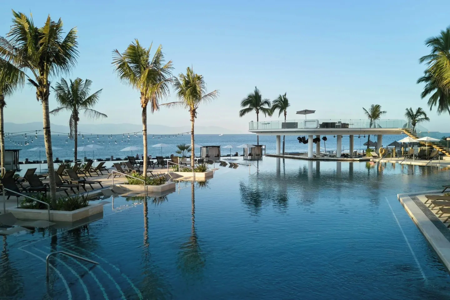 Pool with palms, loungers and ocean backdrop at Marriott Puerto Vallarta Resort & Spa.