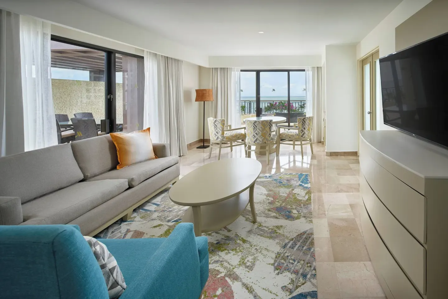 Suite living room with sofa, dining table, TV, and ocean view at Marriott Puerto Vallarta Resort & Spa.