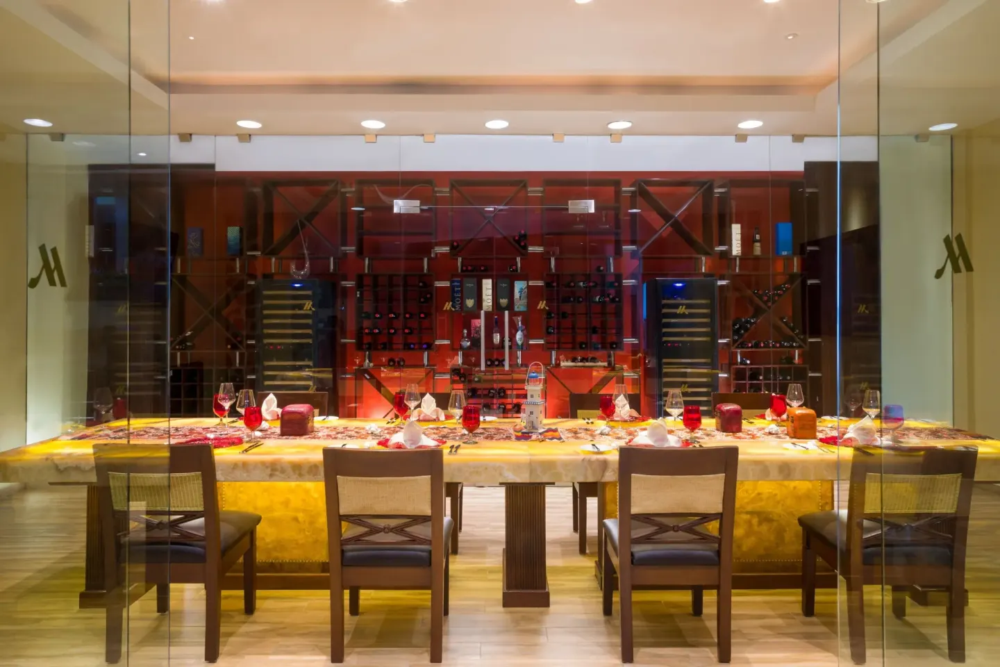Glass-enclosed private dining room at Marriott Puerto Vallarta Resort & Spa with wine displays.