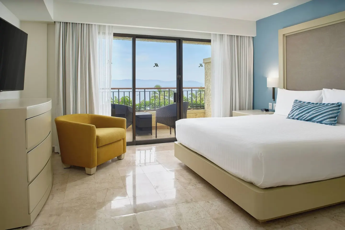 Junior Suite ocean-view king bedroom at Marriott Puerto Vallarta Resort & Spa with balcony seating.