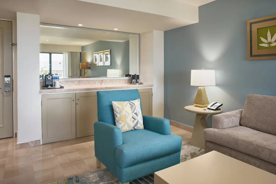 Junior Suite ocean-view lounge at Marriott Puerto Vallarta Resort & Spa with blue armchair and refreshment counter.