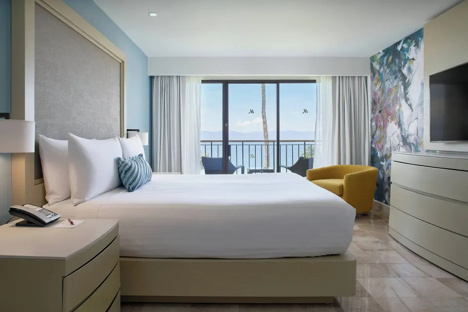 Oceanfront one-bedroom suite bedroom at Marriott Puerto Vallarta Resort & Spa with king bed and balcony.