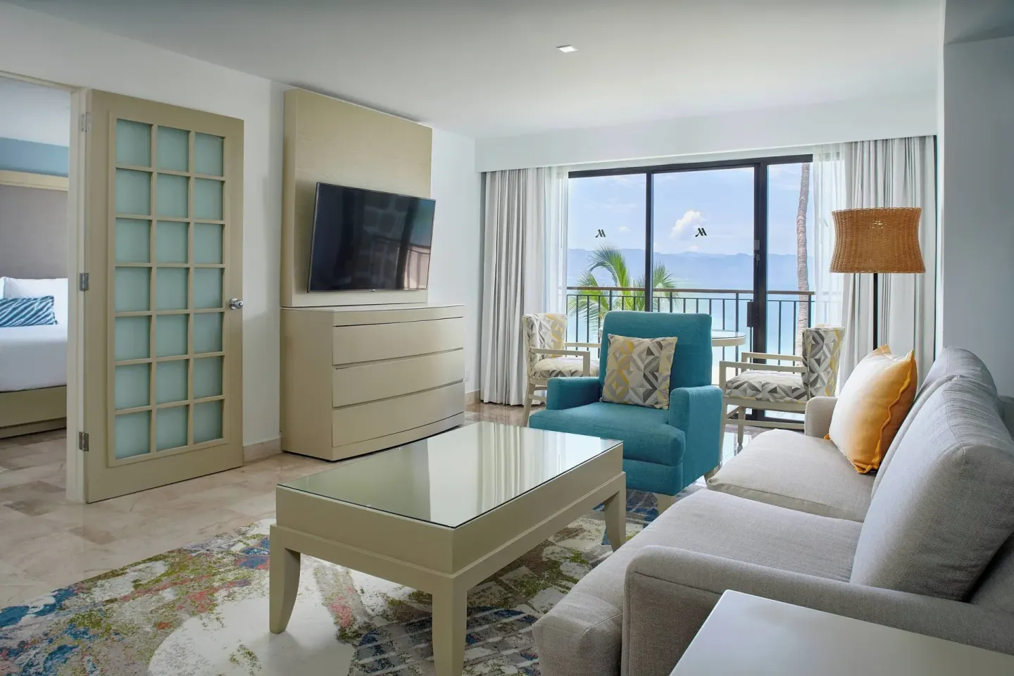 Oceanfront one-bedroom suite living room at Marriott Puerto Vallarta Resort & Spa with sofa and balcony doors.