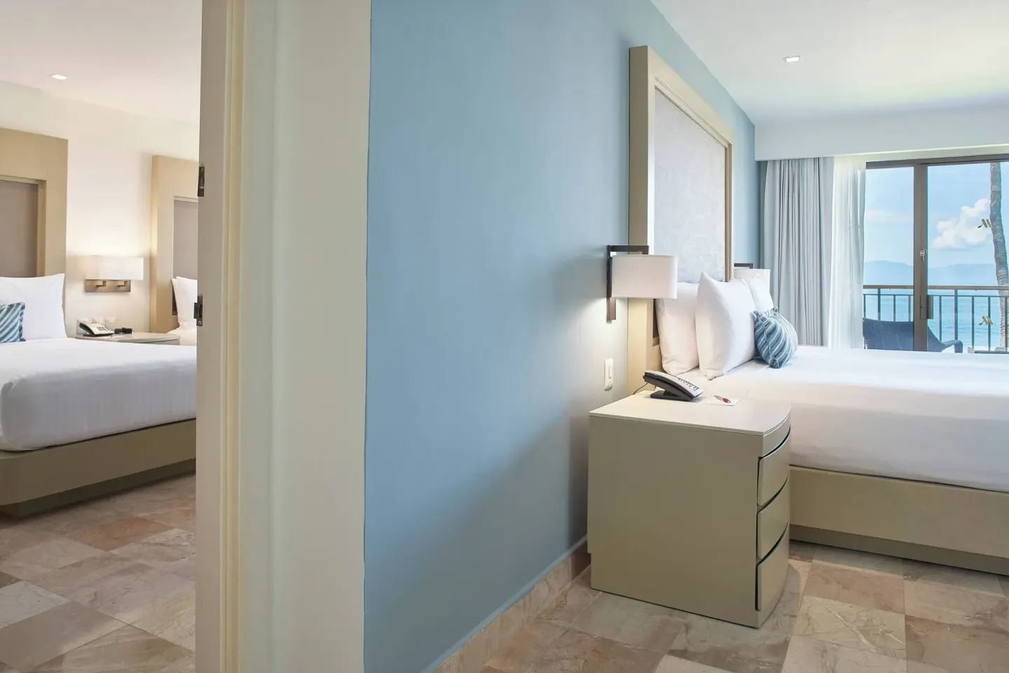 Oceanfront one-bedroom suite bedrooms at Marriott Puerto Vallarta Resort & Spa with beds and balcony view.