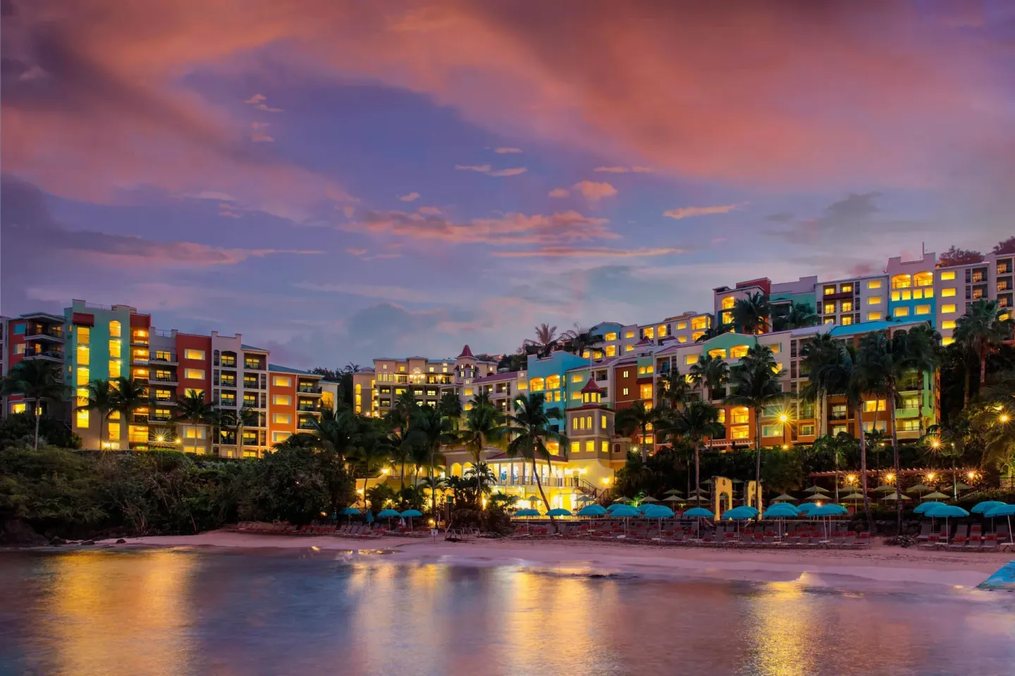 Illuminated resort buildings and beach at sunset at Marriott's Frenchman's Cove.