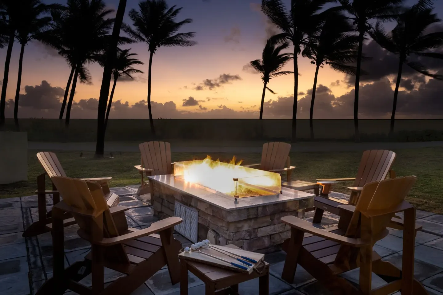 Fire pit seating by palm trees at sunset at Marriott's St. Kitts Beach Club.