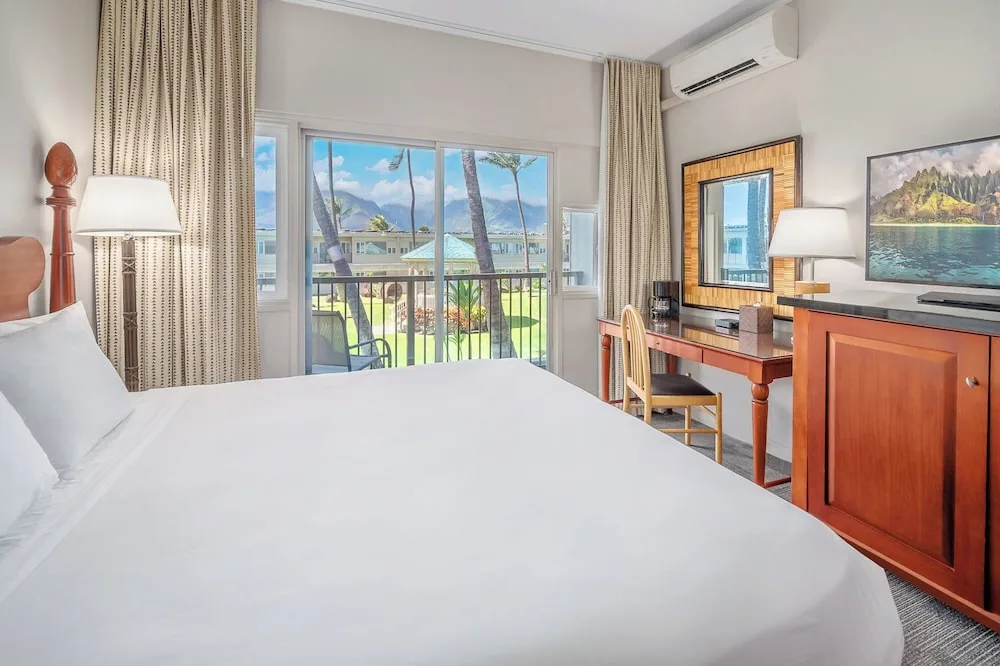 King-bed guest room with balcony doors and garden view at Maui Beach Hotel.
