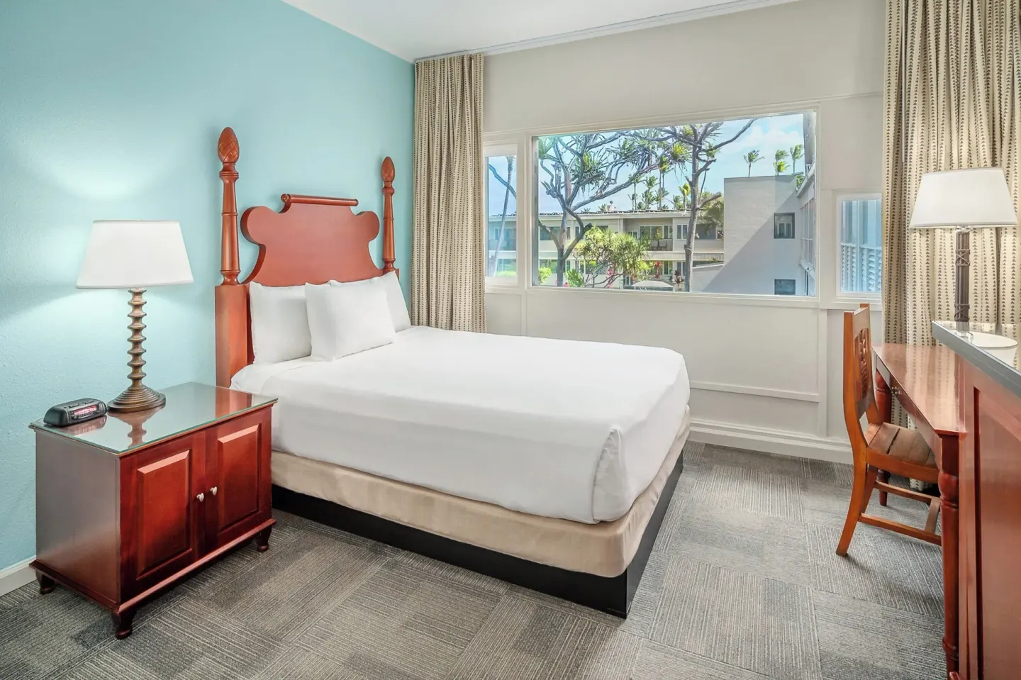 King bed guest room with desk, nightstand, and courtyard-facing window at Maui Beach Hotel.