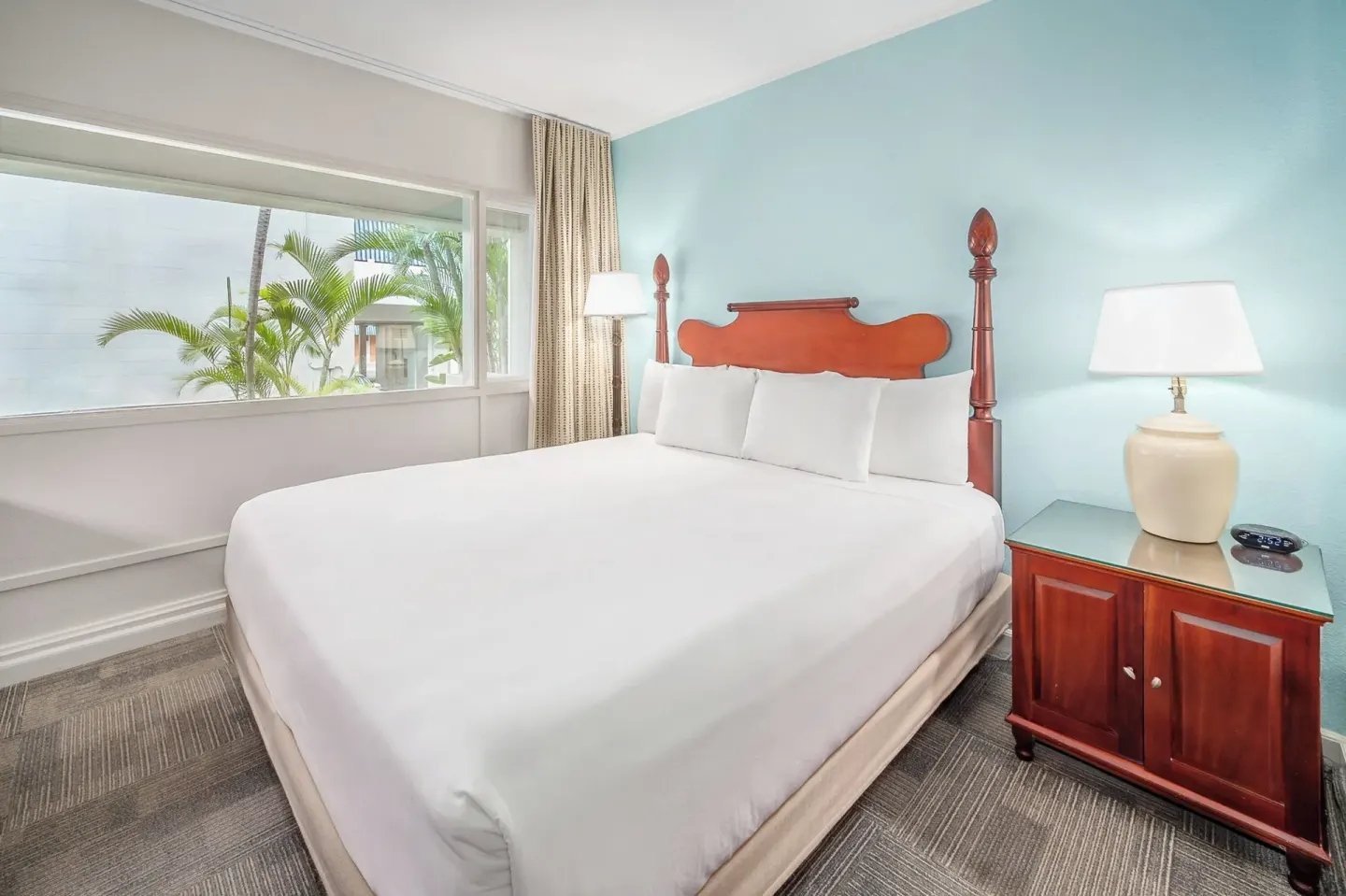 King bed guest room with bedside lamps and courtyard window at Maui Beach Hotel.