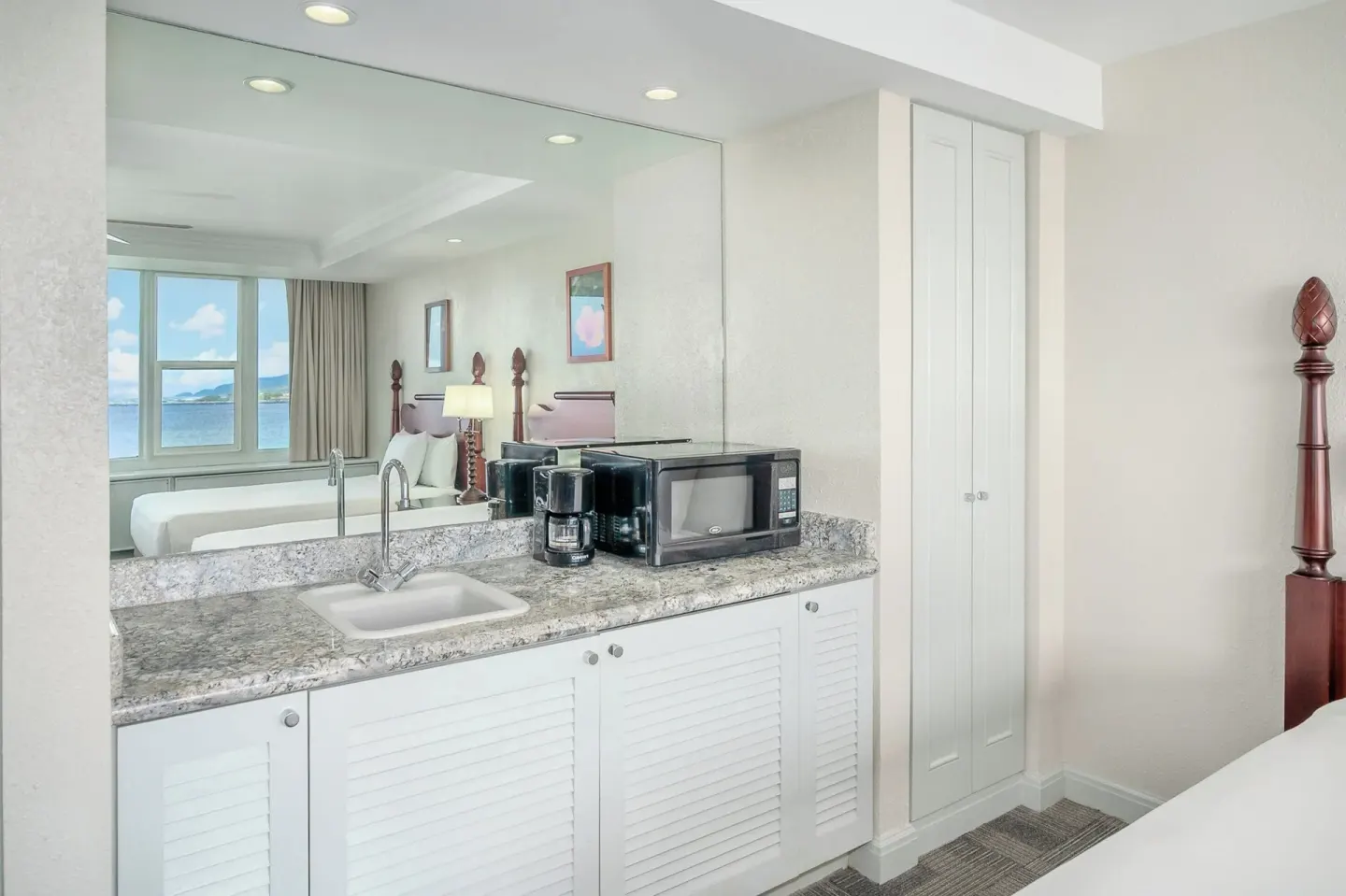 Guest room kitchenette with sink, microwave, coffee maker, and mirror at Maui Beach Hotel.