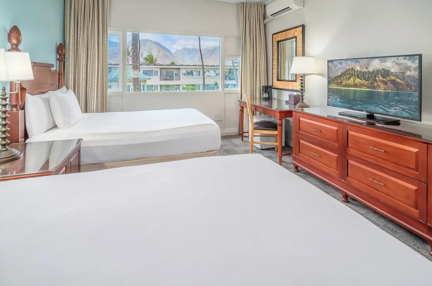 Two-bed guest room with desk, TV, and mountain view at Maui Beach Hotel.