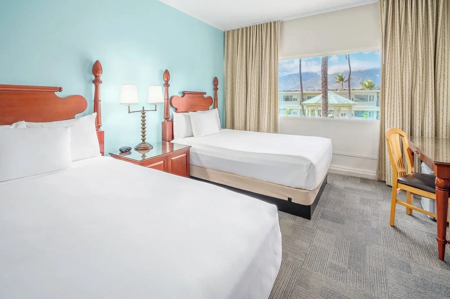 Two-bed guest room with a window facing palms and hotel grounds at Maui Beach Hotel.