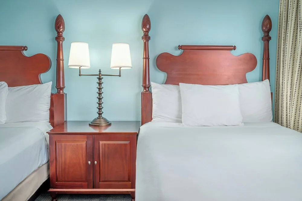 Two beds with wood headboards and shared nightstand at Maui Beach Hotel.
