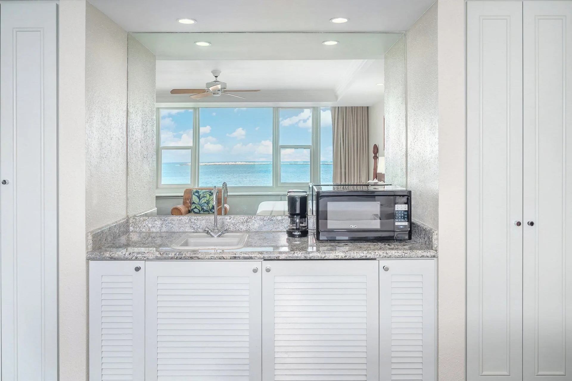 In-room wet bar with sink, microwave, and ocean-view mirror at Maui Beach Hotel.