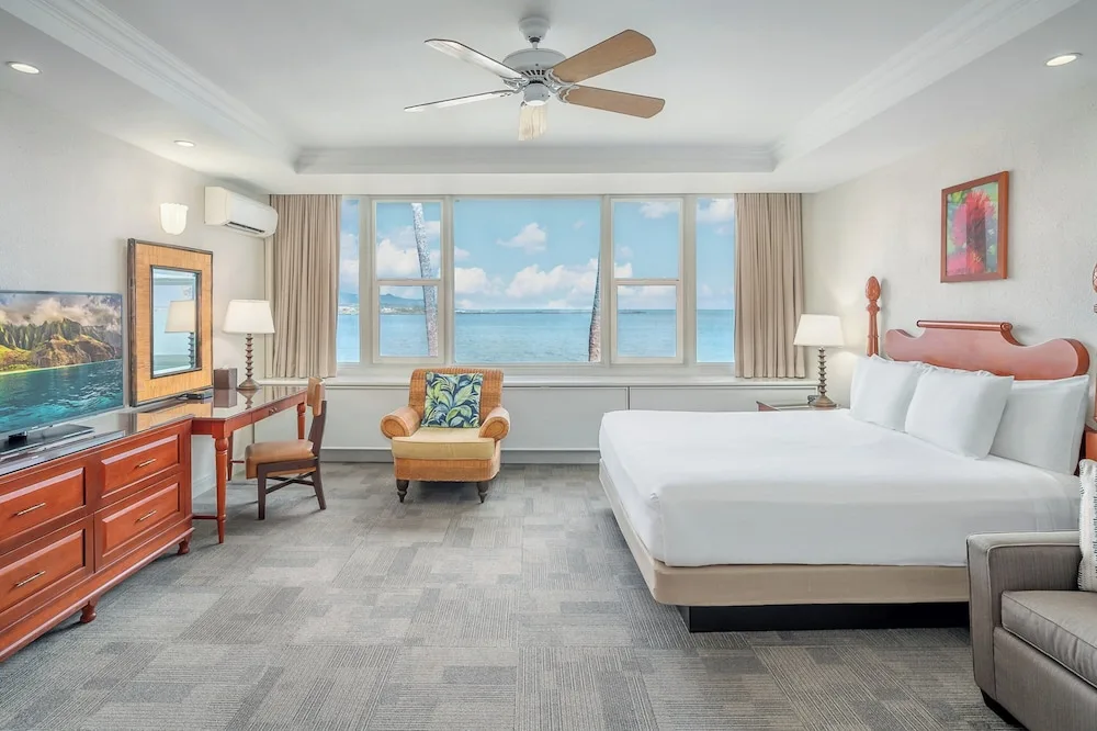King-bed ocean-view guest room with desk, sofa, and armchair at Maui Beach Hotel.