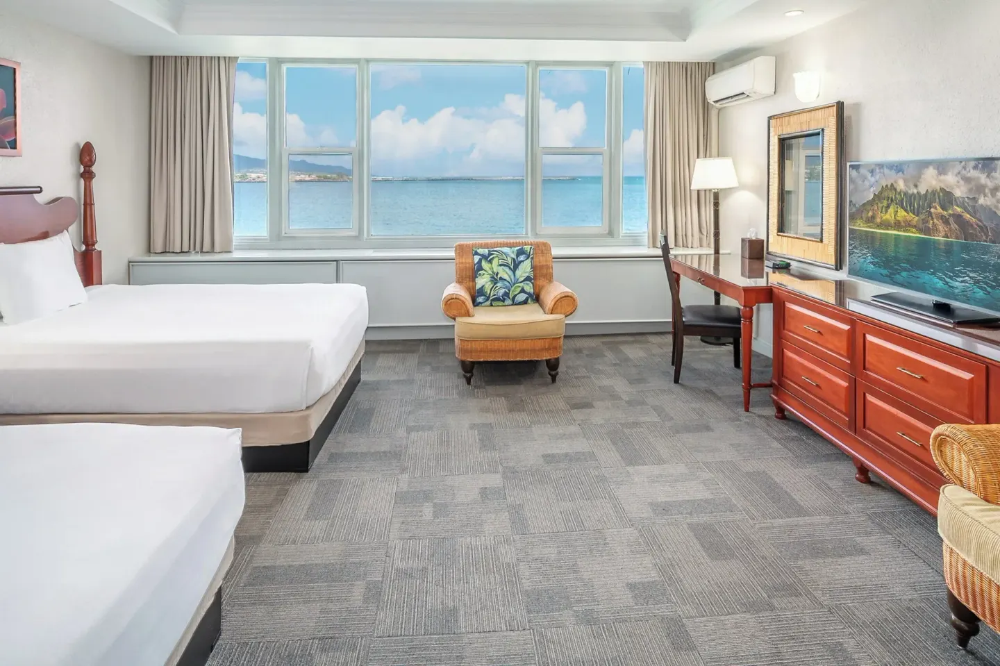 Ocean-view guest room with two beds, desk, dresser, and TV at Maui Beach Hotel.