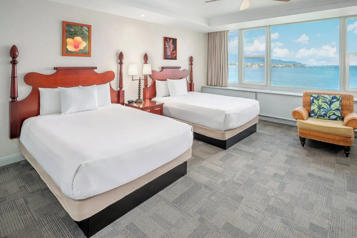 Two-bed ocean-view guest room with wicker chair at Maui Beach Hotel.