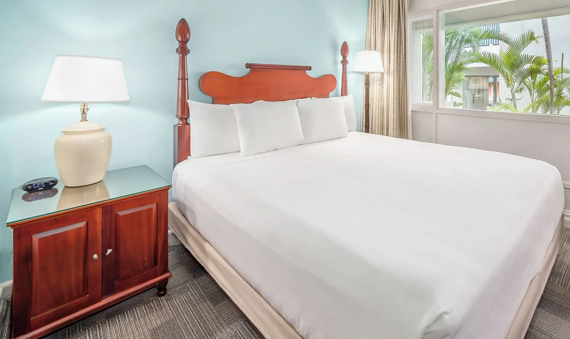 Standard Room One Bed at Maui Beach Hotel with white bedding, wood headboard, nightstand, lamp, and window.