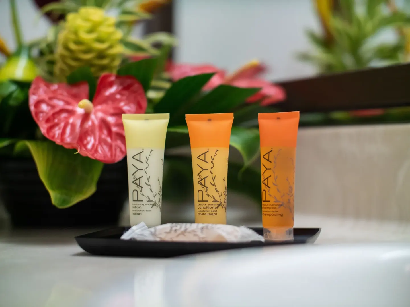 Bath amenities sit on a tray beside tropical flowers at Maui Seaside Hotel.