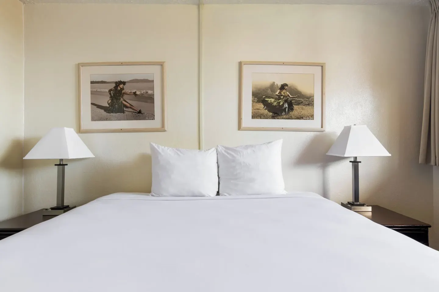 King bed with bedside lamps and framed artwork at Maui Seaside Hotel.