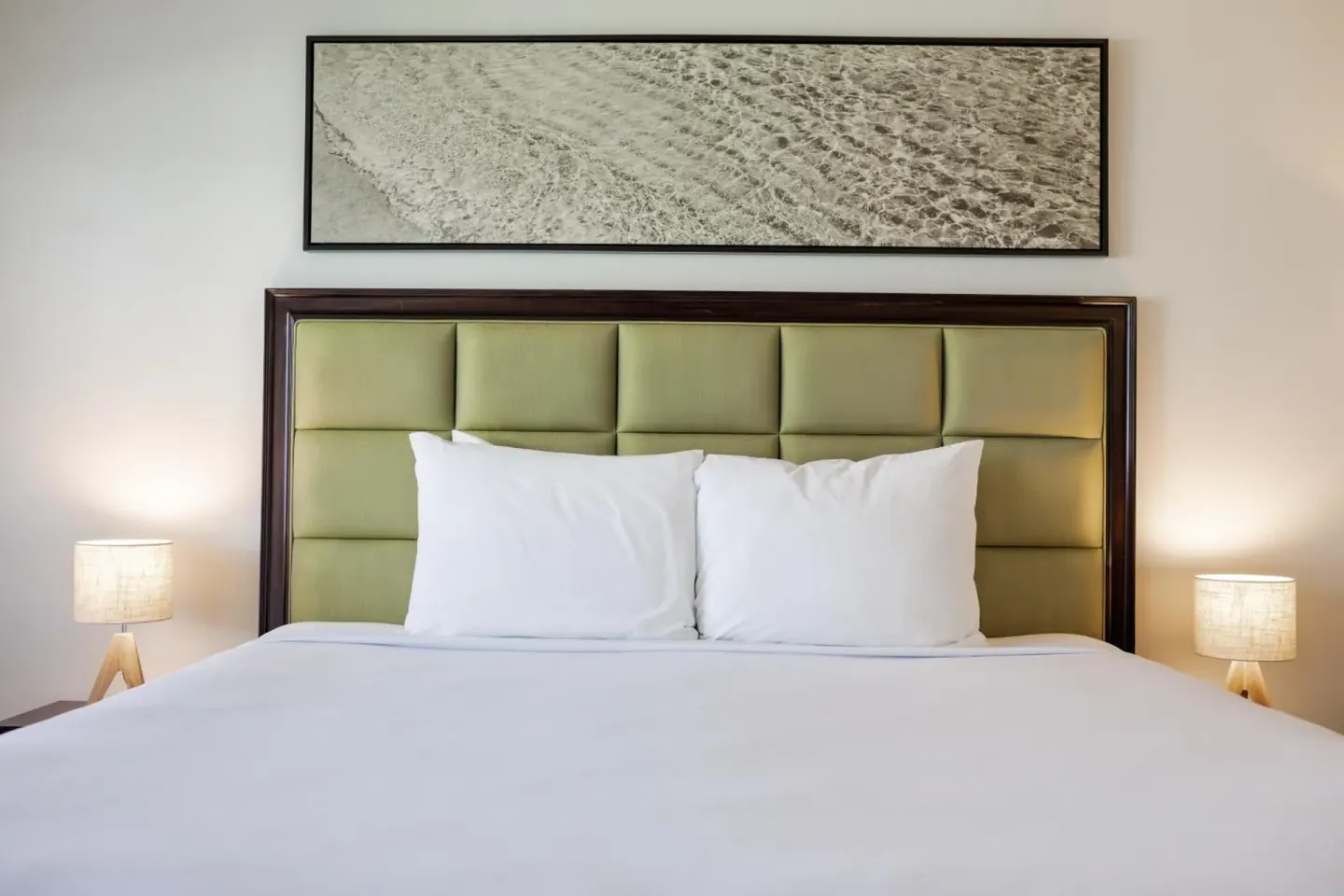 Guest room bed with green headboard and bedside lamps at Maui Seaside Hotel.