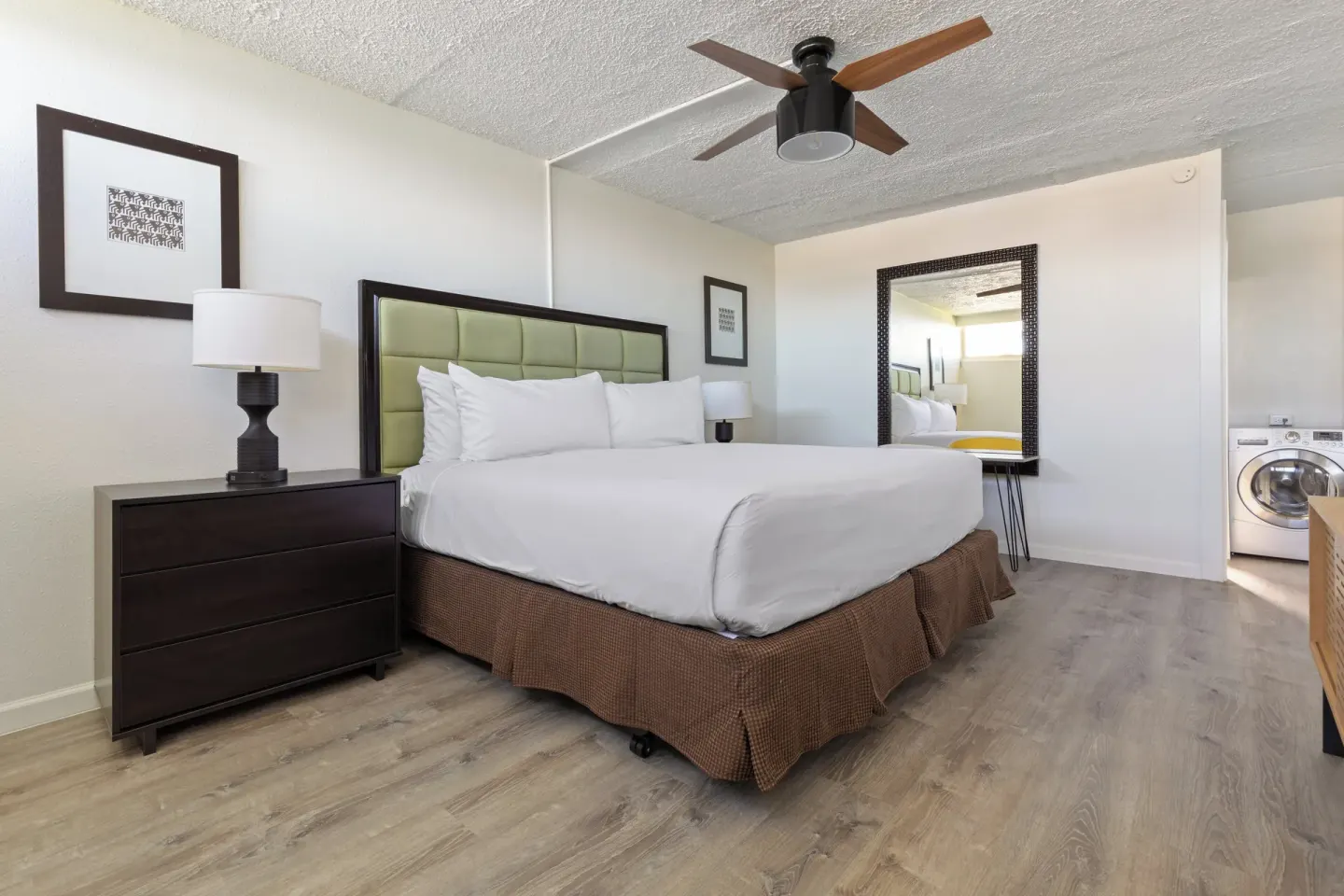 Updated king bed guest room with mirror and laundry area at Maui Seaside Hotel.