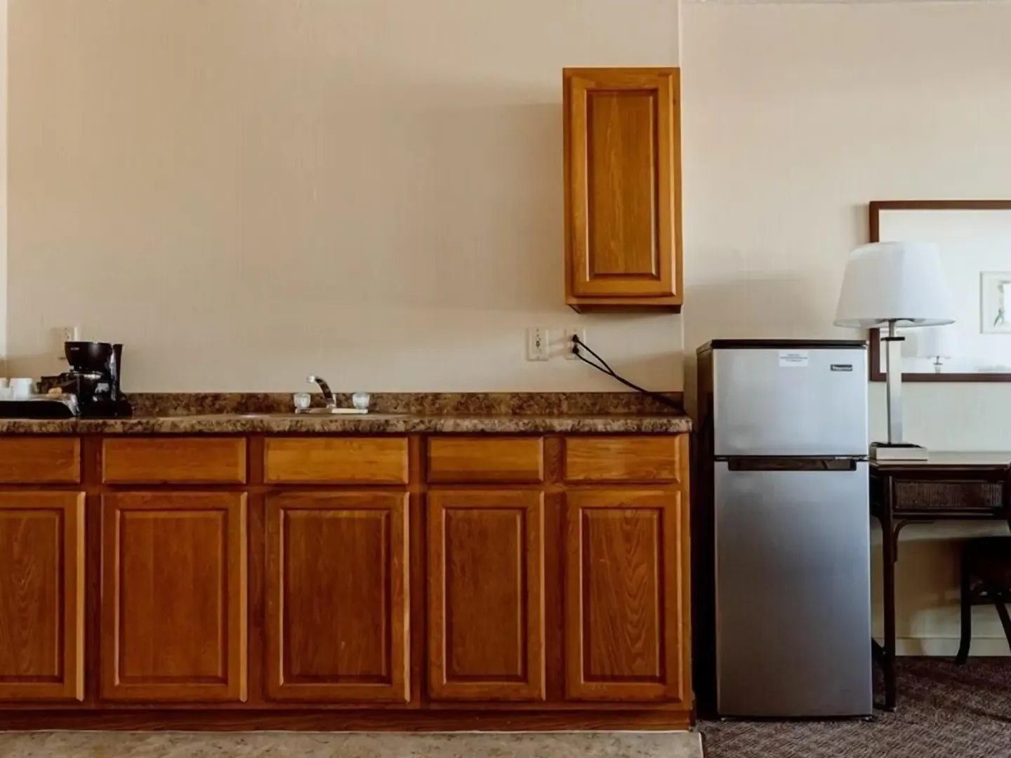 Guest room kitchenette with wood cabinets, sink, coffee maker, and refrigerator at Maui Seaside Hotel.