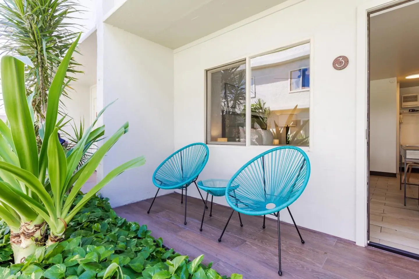 Guest room patio with turquoise chairs and tropical plants at Maui Seaside Hotel.