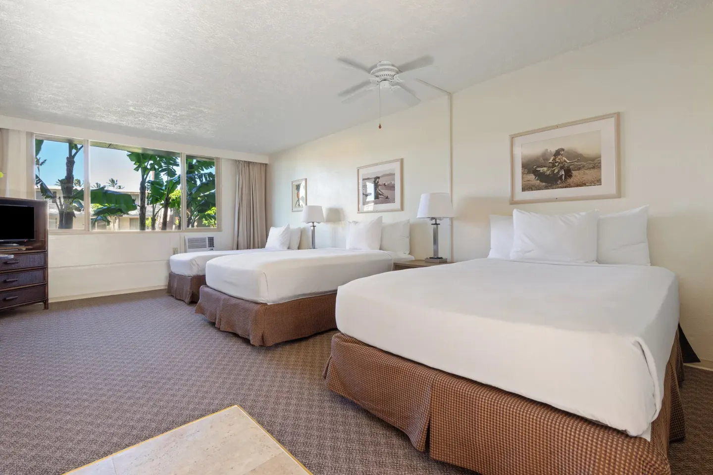Spacious three-bed guest room with large windows at Maui Seaside Hotel.