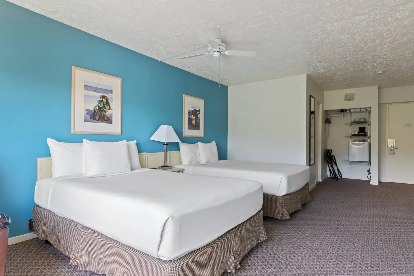 Two-bed guest room with turquoise wall and open closet at Maui Seaside Hotel.