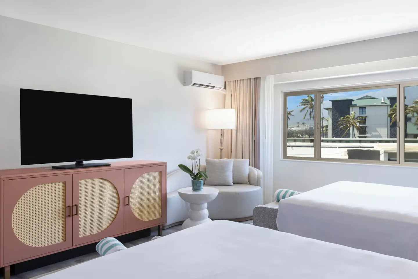 Guest room with two beds, TV, seating, and a window view at Maui Seaside Hotel.