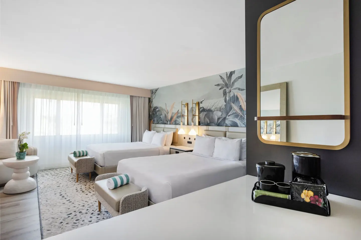 Two-bed guest room with vanity, coffee setup, and sitting area at Maui Seaside Hotel.