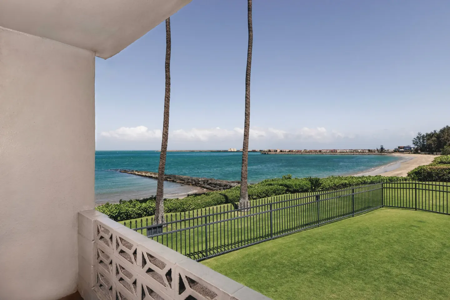 Ocean, beach, palms, and lawn are seen from a balcony at Maui Seaside Hotel.