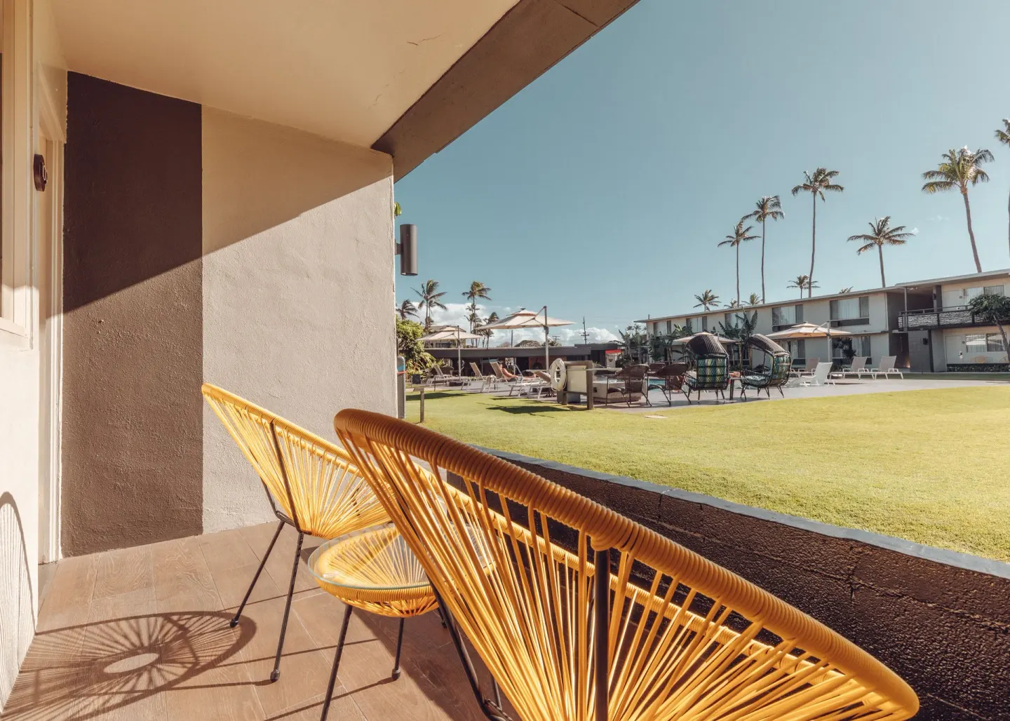 Yellow patio chairs overlook the lawn and pool area at Maui Seaside Hotel.
