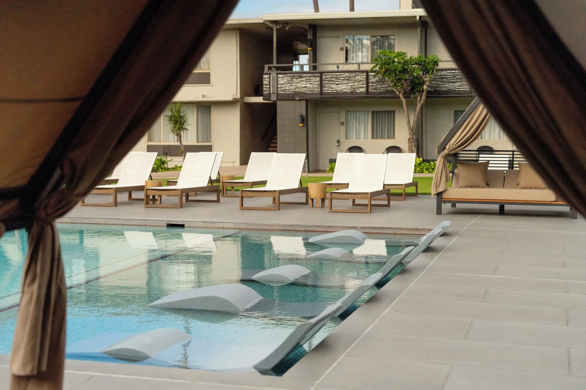 Pool with in-water loungers and cabana seating at Maui Seaside Hotel.