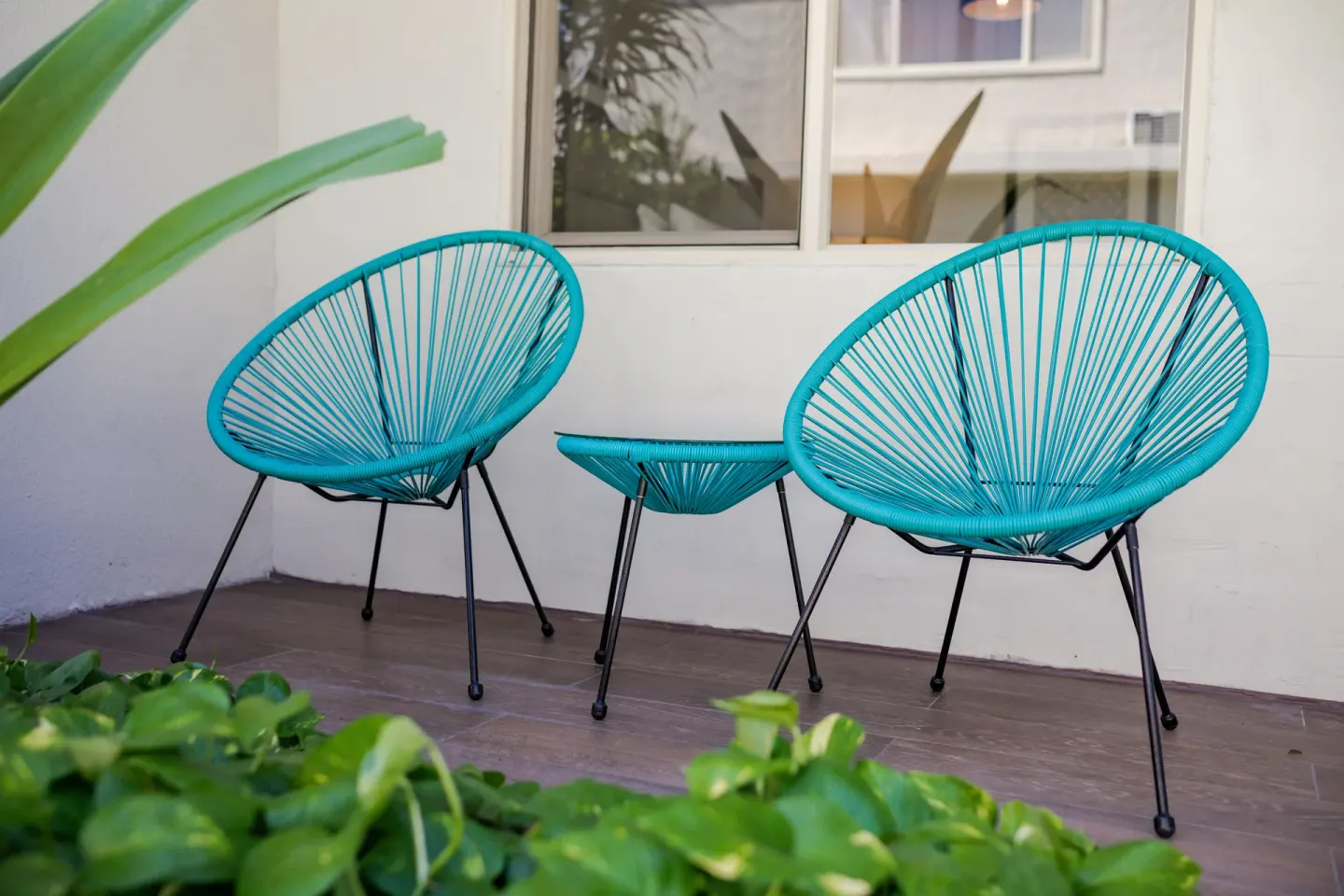 Turquoise patio chairs and small table outside a room at Maui Seaside Hotel.