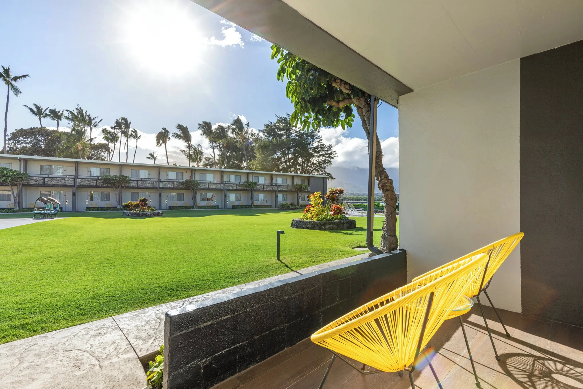 Poolside room patio with yellow chair and lawn view at Maui Seaside Hotel.