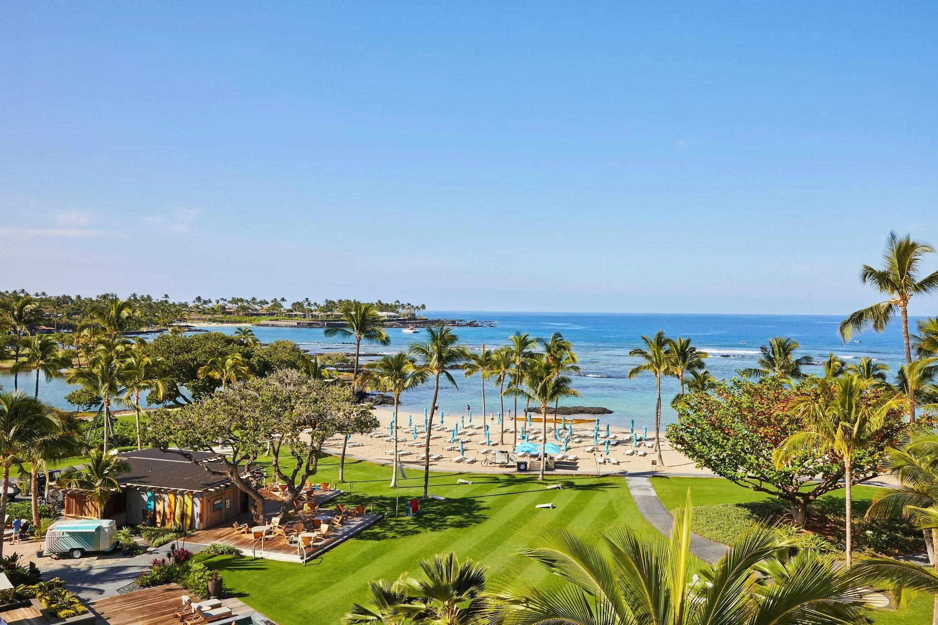 Beachfront lawn, palm trees, sandy shore, and blue ocean at Mauna Lani.