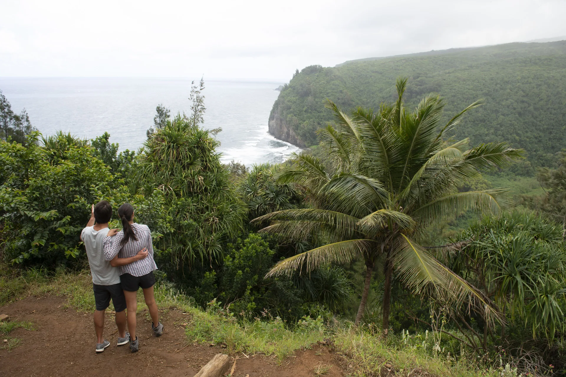 Couple viewing a lush coastal cliff and ocean from a trail near Mauna Lani.