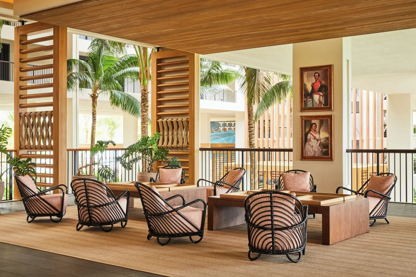Covered lobby lounge with woven chairs, palm views, and framed portraits at Mauna Lani.