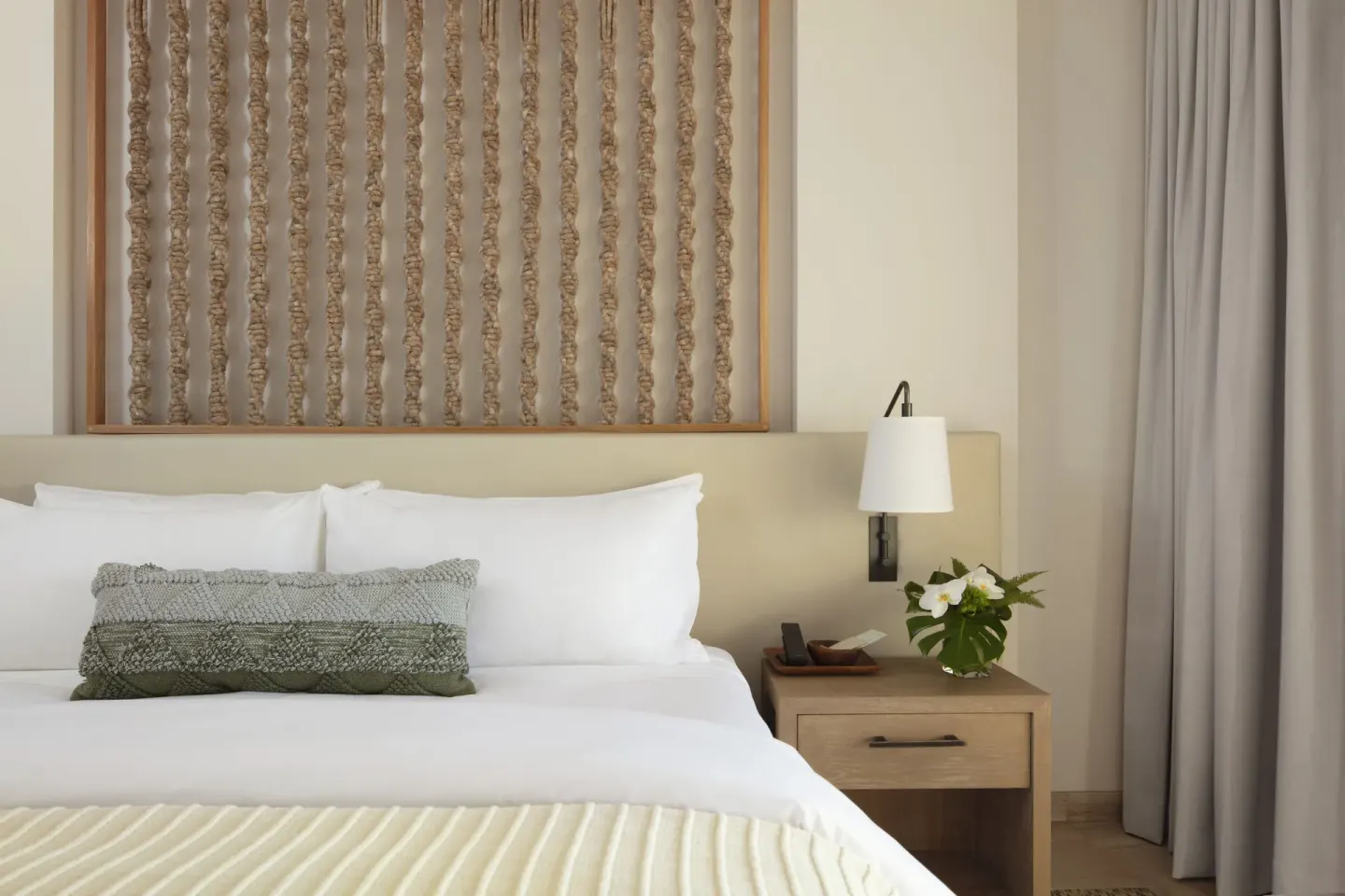 Close-up of a king bed and bedside table with flowers at Mauna Lani.