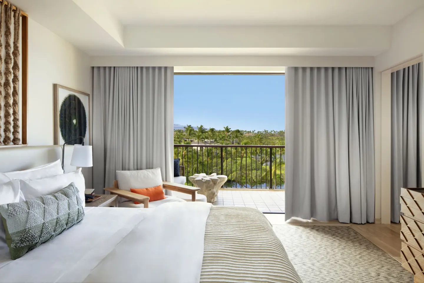 King guest room with open balcony curtains and tropical view at Mauna Lani.