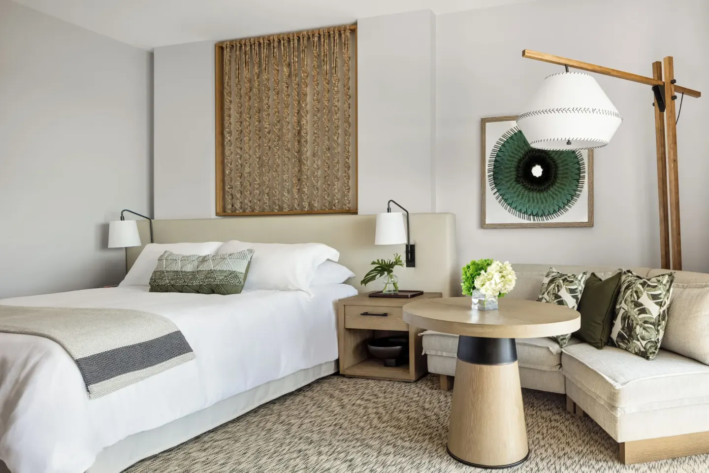 King bed guest room with sofa, round table, and wall art at Mauna Lani.